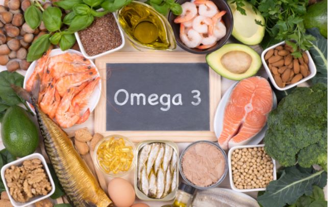 Wooden board with "omega 3" written on it with food surrounding it